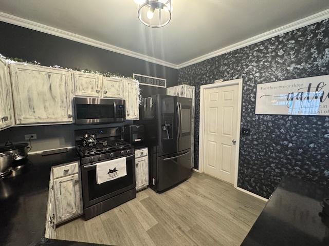 kitchen with ornamental molding, light wood-type flooring, and black appliances