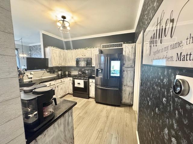 kitchen with an inviting chandelier, ornamental molding, appliances with stainless steel finishes, and light hardwood / wood-style floors