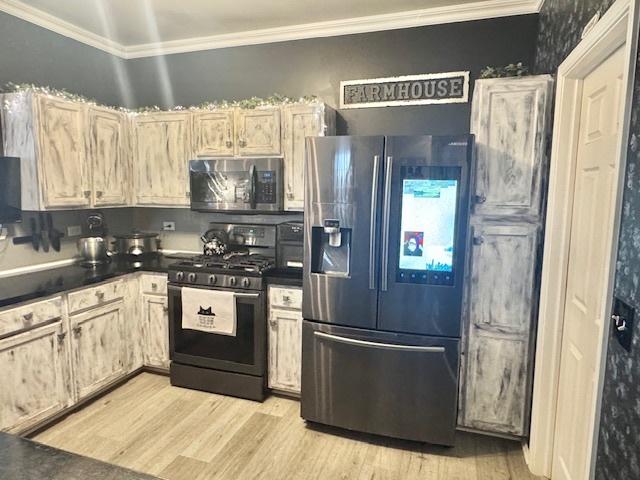 kitchen featuring stainless steel appliances, ornamental molding, and light hardwood / wood-style flooring