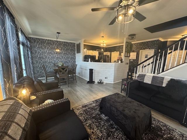 living room featuring crown molding, wood-type flooring, and ceiling fan