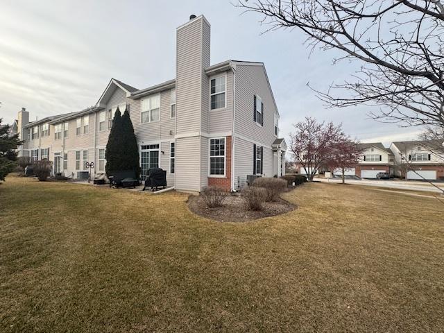 rear view of property featuring central AC unit and a lawn