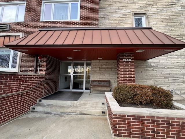 view of exterior entry featuring metal roof, brick siding, a standing seam roof, and stone siding