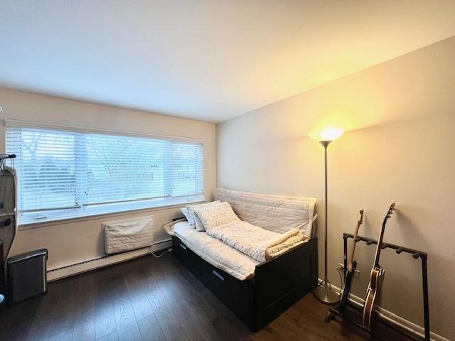 living area featuring dark wood-style floors, baseboards, and a baseboard heating unit