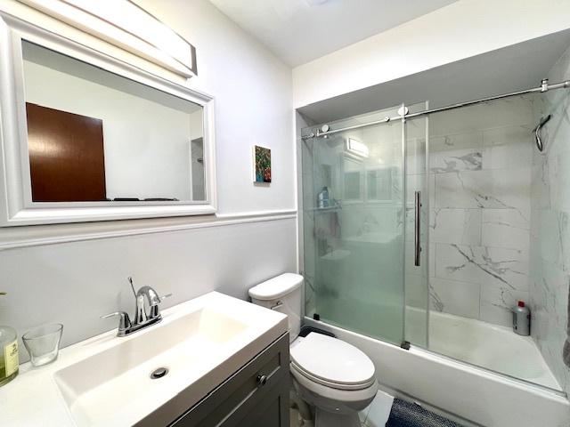 full bathroom with toilet, shower / bath combination with glass door, and vanity