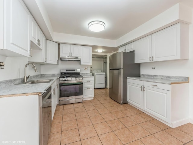 kitchen with light tile patterned floors, sink, appliances with stainless steel finishes, white cabinetry, and washer / clothes dryer