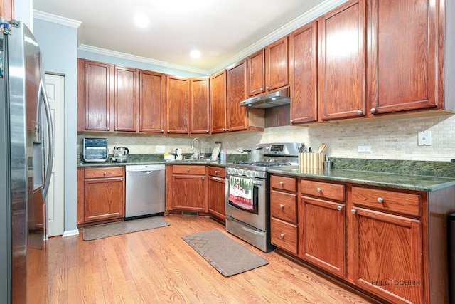 kitchen with tasteful backsplash, sink, ornamental molding, stainless steel appliances, and light wood-type flooring