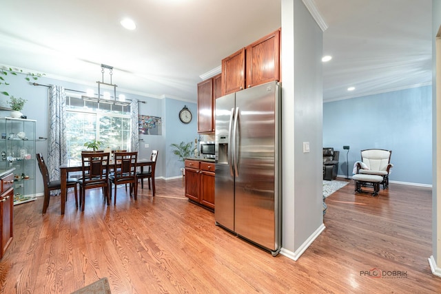 kitchen with stainless steel appliances, ornamental molding, decorative light fixtures, and light hardwood / wood-style flooring