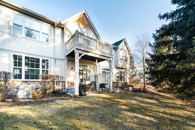 rear view of house with a balcony, a yard, and central air condition unit