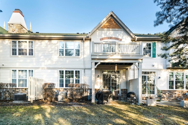 rear view of property with a balcony, a yard, and central AC unit