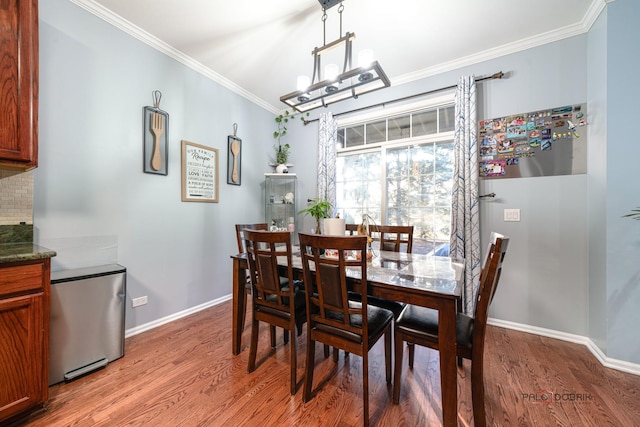 dining area with hardwood / wood-style flooring, crown molding, and a notable chandelier