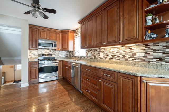 kitchen with sink, appliances with stainless steel finishes, backsplash, dark hardwood / wood-style floors, and light stone counters