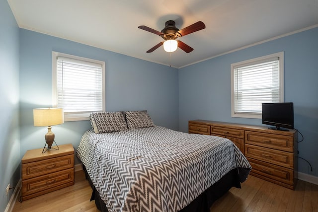 bedroom featuring multiple windows, crown molding, and light hardwood / wood-style floors