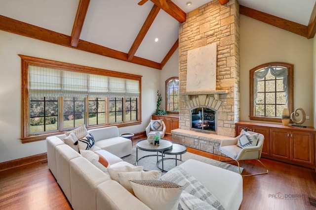 living room with wood-type flooring, a stone fireplace, high vaulted ceiling, and beam ceiling