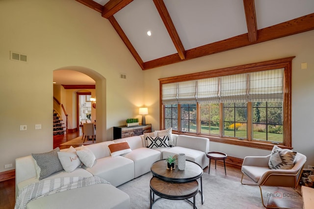 living room with beamed ceiling, light hardwood / wood-style floors, and high vaulted ceiling