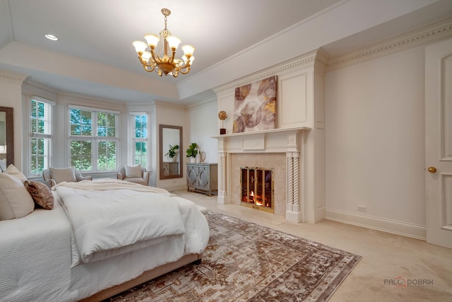 carpeted bedroom featuring a tray ceiling, a high end fireplace, ornamental molding, and a chandelier