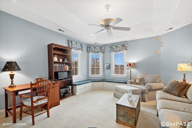 carpeted living room featuring ceiling fan and a tray ceiling