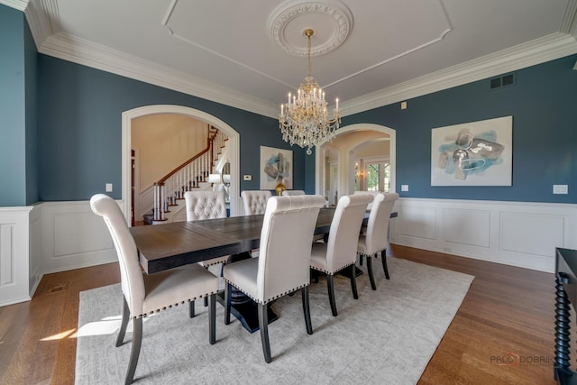 dining room with an inviting chandelier, hardwood / wood-style flooring, and ornamental molding