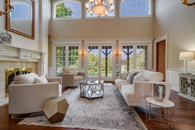 living room with a towering ceiling, dark wood-type flooring, a notable chandelier, and french doors