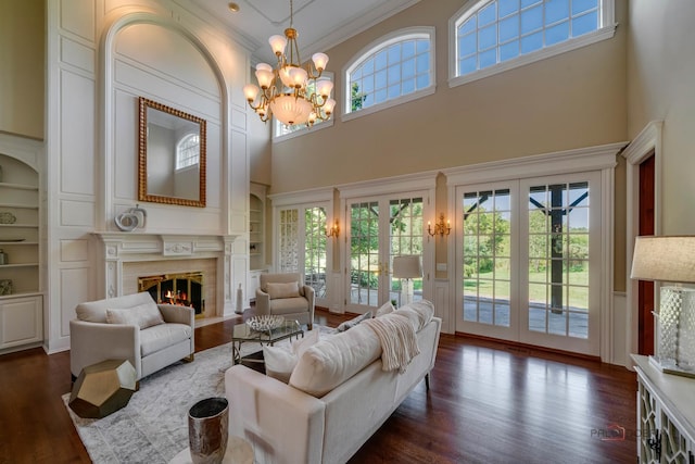 living room with built in shelves, crown molding, a chandelier, dark hardwood / wood-style floors, and a high end fireplace