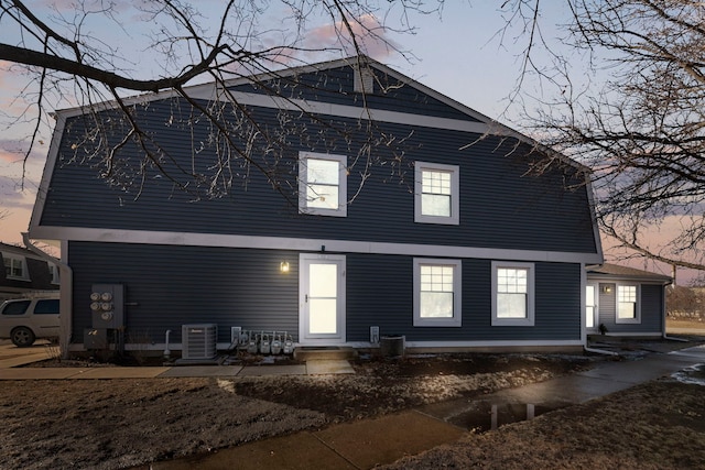 back house at dusk featuring central AC unit