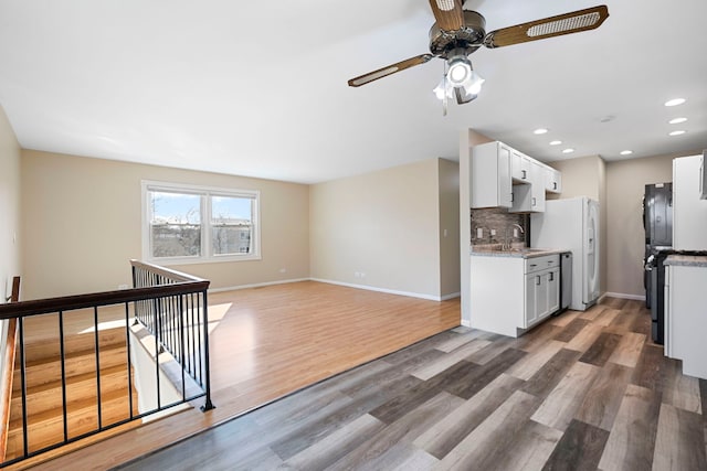 kitchen with white cabinetry, backsplash, white refrigerator, wood-type flooring, and light stone countertops