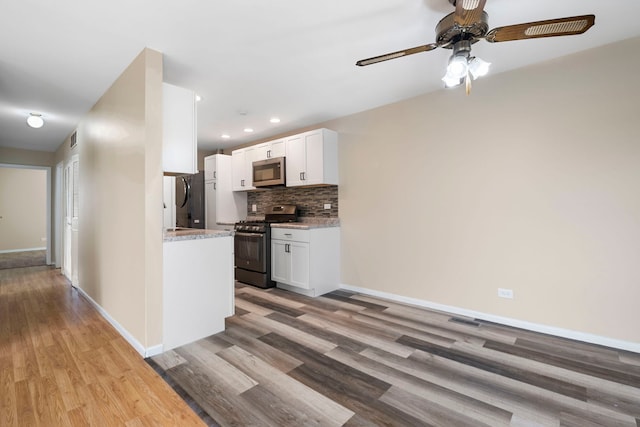 kitchen with light stone counters, decorative backsplash, white cabinets, and appliances with stainless steel finishes