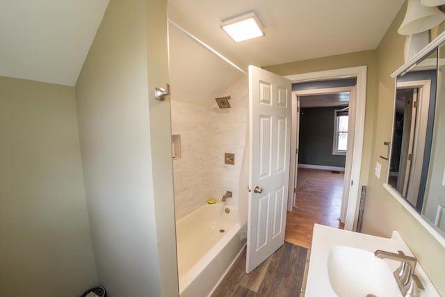 bathroom with lofted ceiling, hardwood / wood-style floors, vanity, and tiled shower / bath