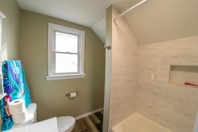 bathroom featuring lofted ceiling, hardwood / wood-style floors, tiled shower / bath combo, and toilet