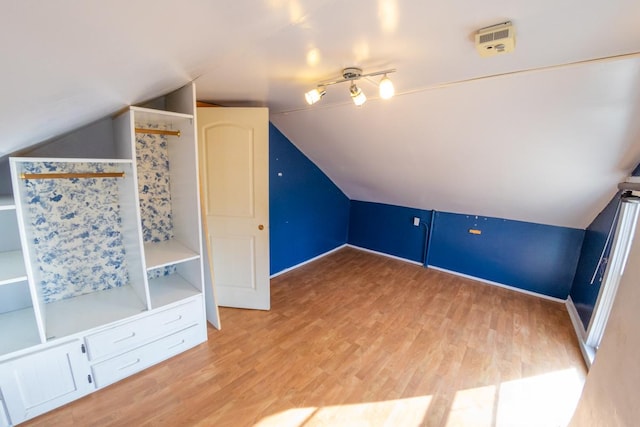 additional living space featuring lofted ceiling and light hardwood / wood-style flooring