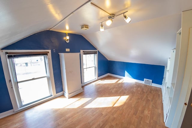 additional living space featuring vaulted ceiling and light wood-type flooring