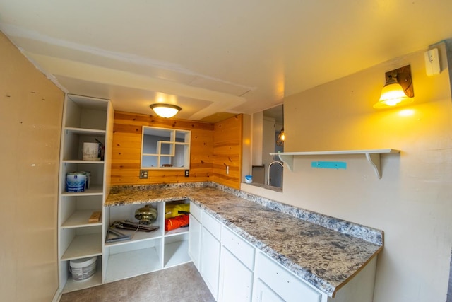 kitchen with white cabinetry, light tile patterned floors, and light stone counters