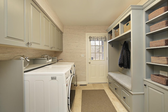 clothes washing area featuring cabinets, sink, washing machine and dryer, and light tile patterned floors