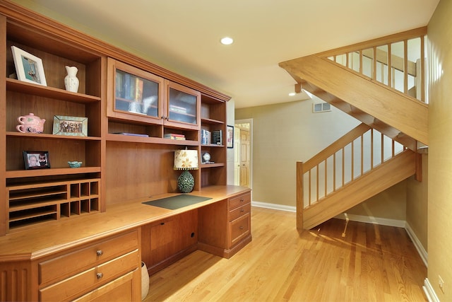 office space with built in desk and light wood-type flooring