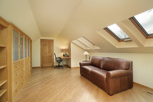 interior space featuring lofted ceiling with skylight and light wood-type flooring