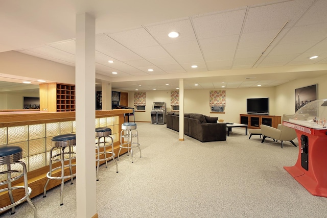 living room with indoor bar, carpet, and a drop ceiling