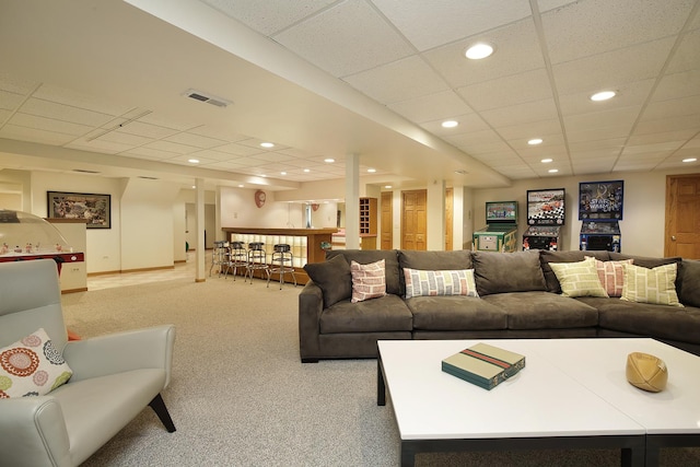 carpeted living room featuring a paneled ceiling and indoor bar