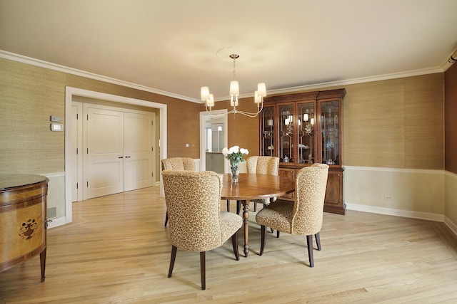 dining area with ornamental molding, light hardwood / wood-style floors, and a notable chandelier