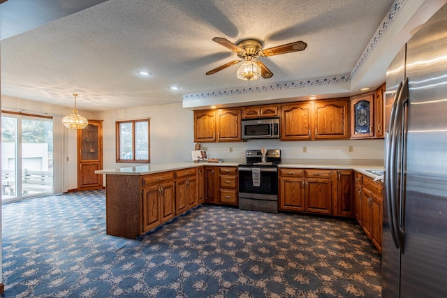 kitchen featuring hanging light fixtures, kitchen peninsula, a textured ceiling, and appliances with stainless steel finishes