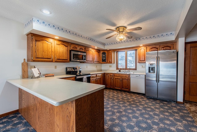 kitchen with sink, a textured ceiling, appliances with stainless steel finishes, kitchen peninsula, and ceiling fan