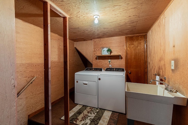 laundry room featuring independent washer and dryer, sink, and wood walls