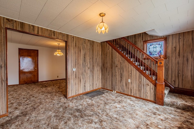 carpeted spare room with wood walls