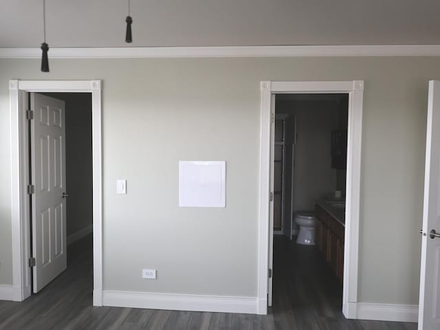 unfurnished bedroom with dark hardwood / wood-style flooring, ornamental molding, and ensuite bathroom