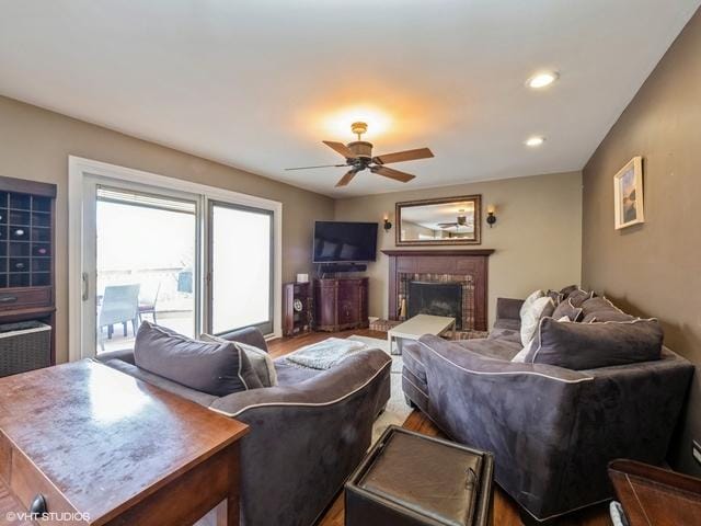 living room featuring a brick fireplace, hardwood / wood-style floors, and ceiling fan