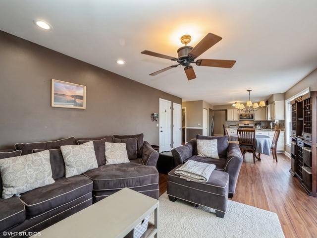 living room with ceiling fan with notable chandelier and light hardwood / wood-style flooring