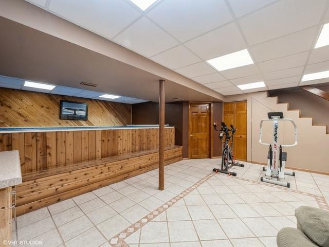 workout room featuring a drop ceiling, tile patterned floors, and wood walls