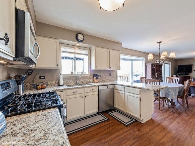 kitchen featuring pendant lighting, sink, stainless steel appliances, dark hardwood / wood-style flooring, and kitchen peninsula