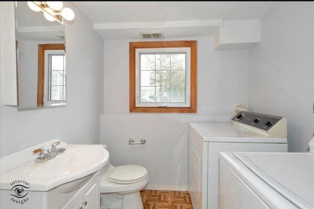 bathroom featuring vanity, parquet flooring, washing machine and dryer, and toilet