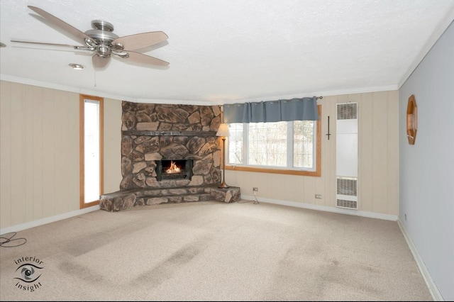 unfurnished living room featuring crown molding, carpet, a stone fireplace, and a textured ceiling