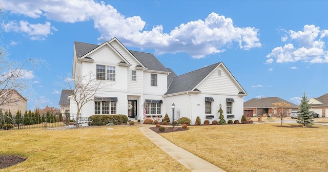 traditional-style house with board and batten siding, a shingled roof, a front yard, and fence