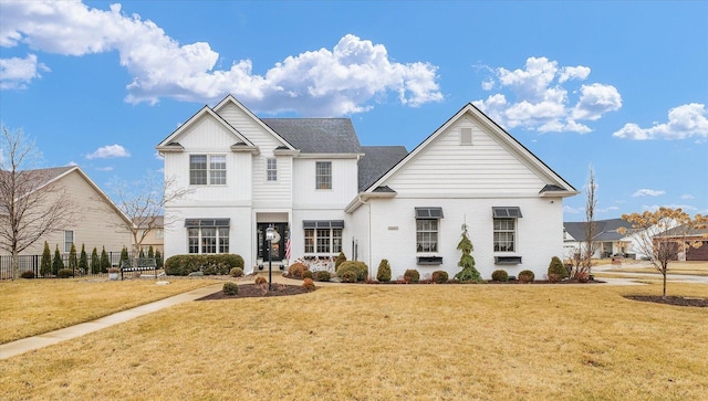 traditional-style home featuring brick siding, board and batten siding, a front yard, and fence